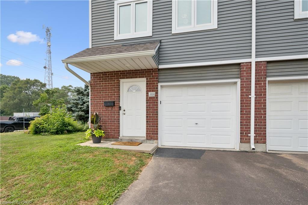 Brick and siding exterior with an attached garage, white entry door, and concrete front walkway