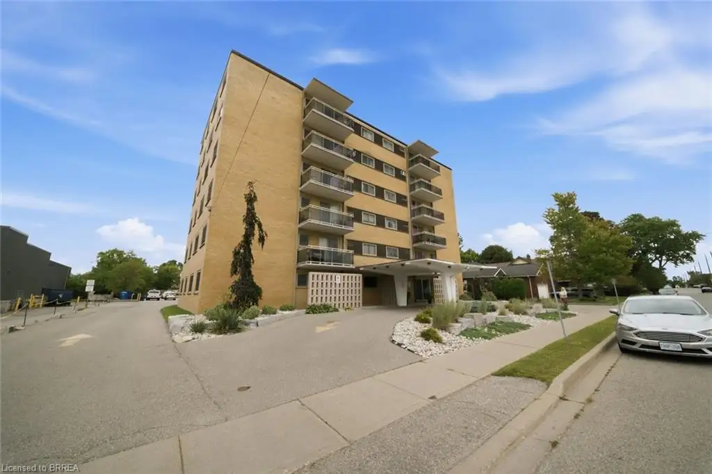 Multi-story building featuring a brick exterior, multiple balconies with glass railings, and a covered entrance