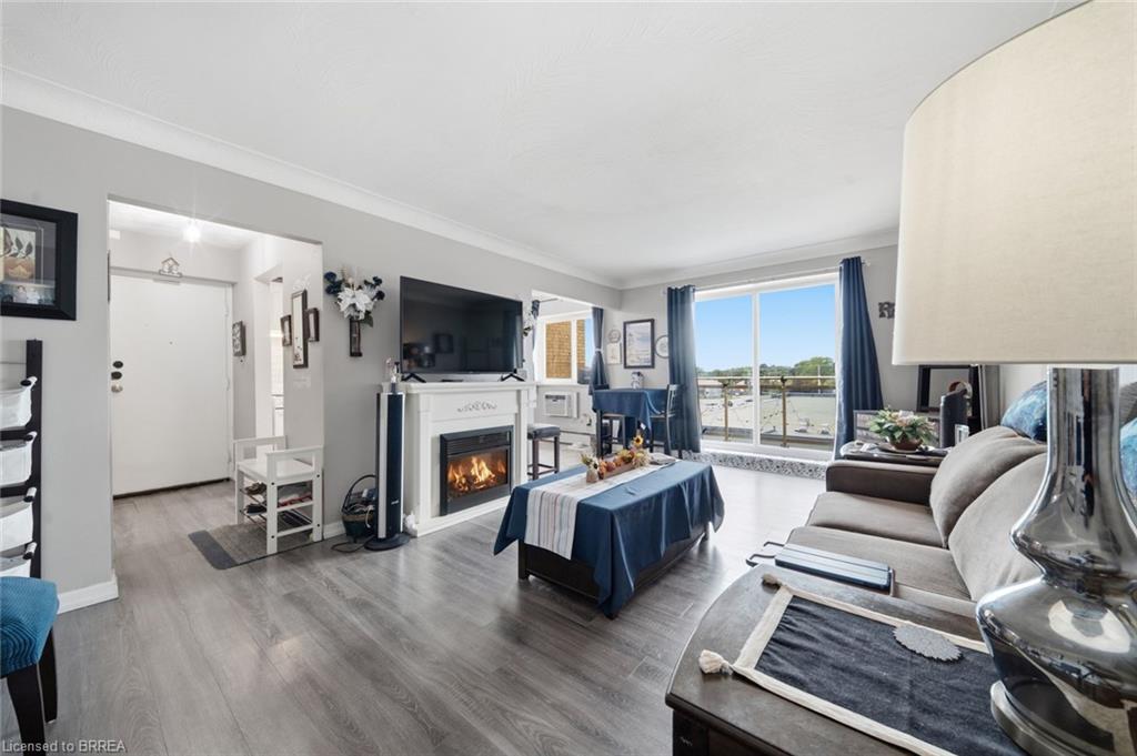Living area featuring wood-finish flooring, a white mantel, and an electric fireplace