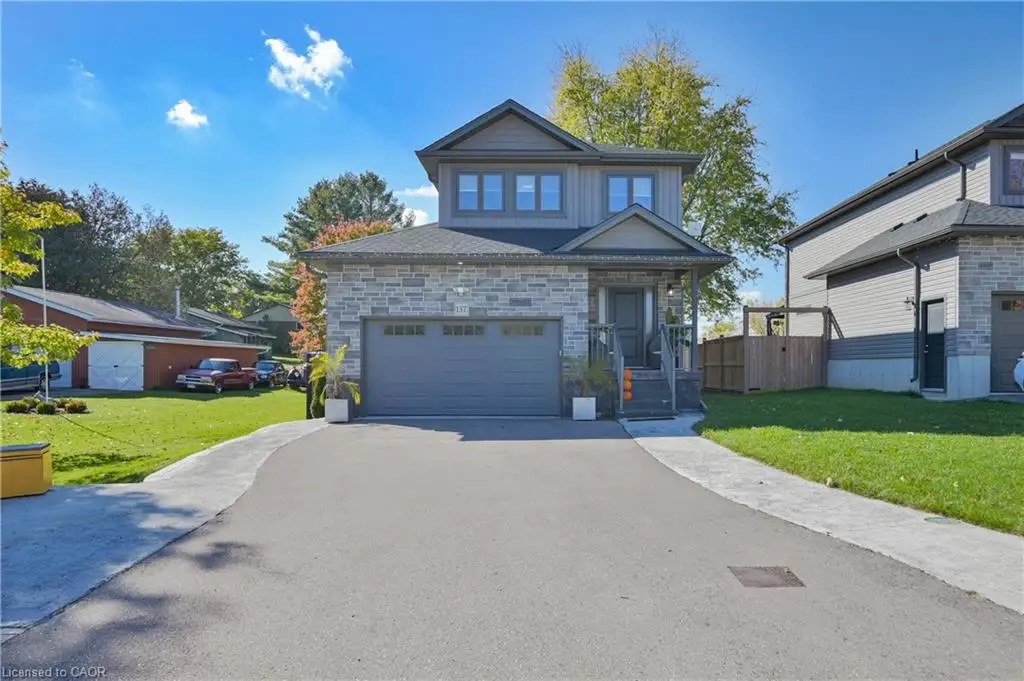 Two-story residence featuring a stone and horizontal siding facade, asphalt-paved driveway, double-car garage, and covered front entry