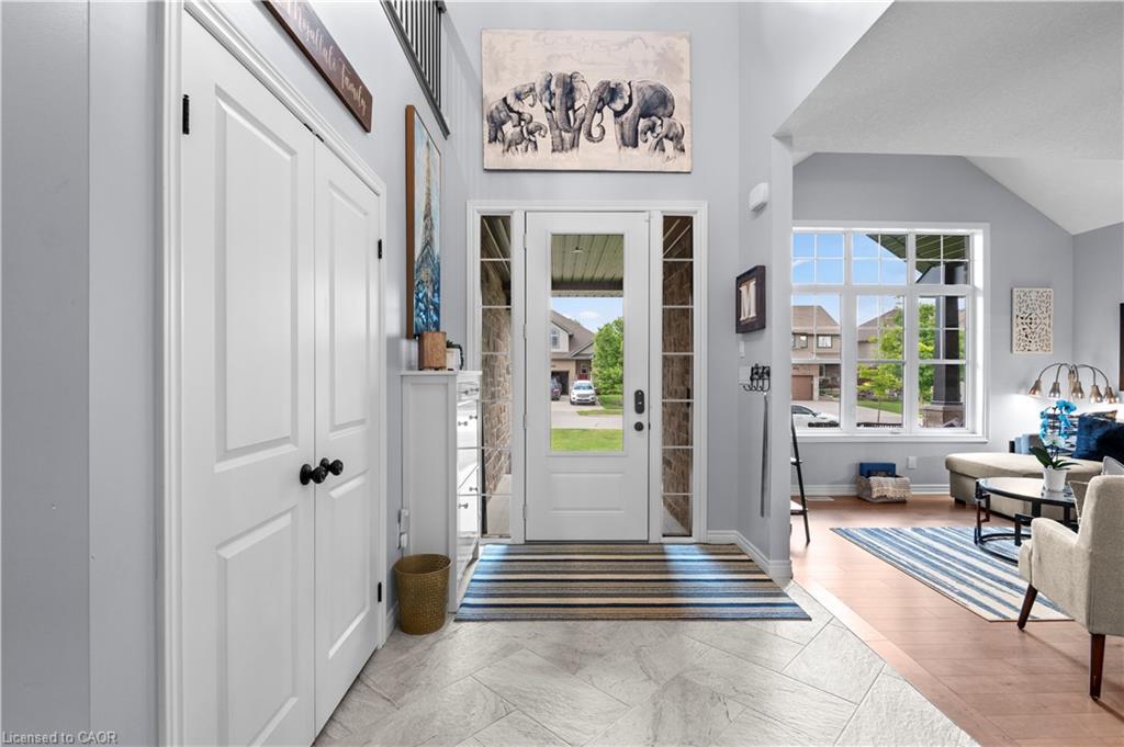 Bright entry foyer featuring high ceilings, light-toned tile flooring, and a glass-paneled front door