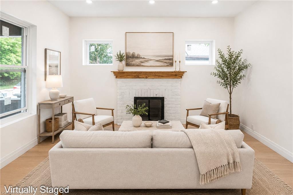 White brick fireplace with a wood mantle, recessed lighting, wood-finish flooring, and multiple windows