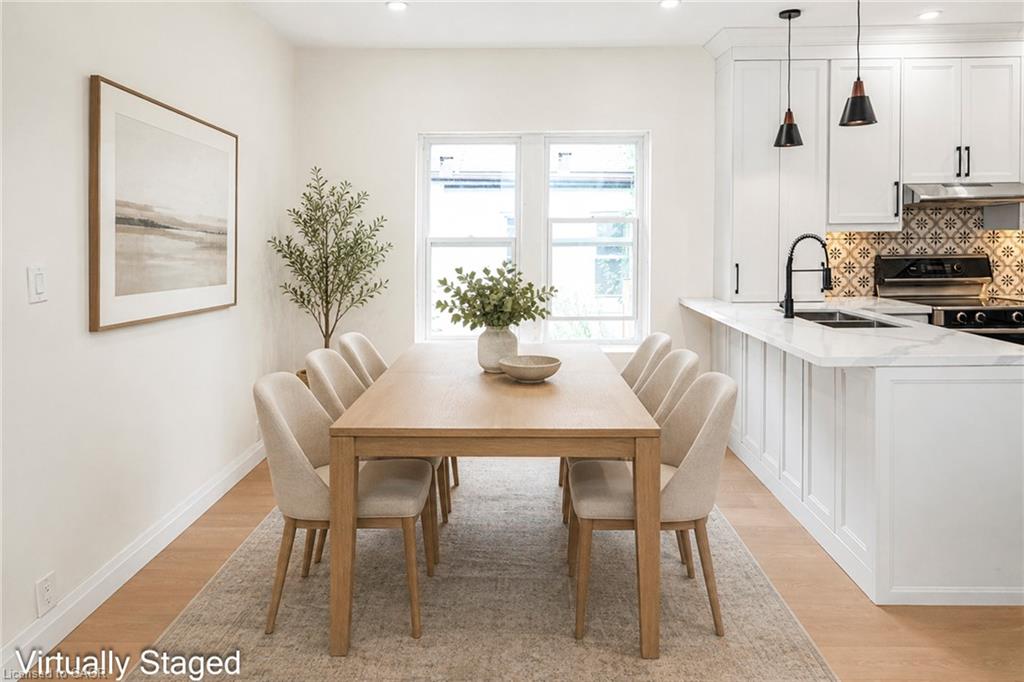 Open-concept kitchen and dining area featuring light wood-finish flooring, white cabinetry, a patterned tile backsplash, and a kitchen island with a built-in sink and countertop