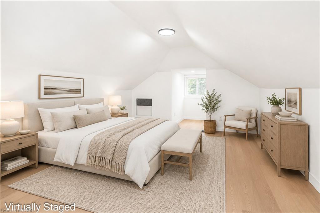 Vaulted ceiling with recessed lighting, light wood-finish flooring, and a window providing natural illumination
