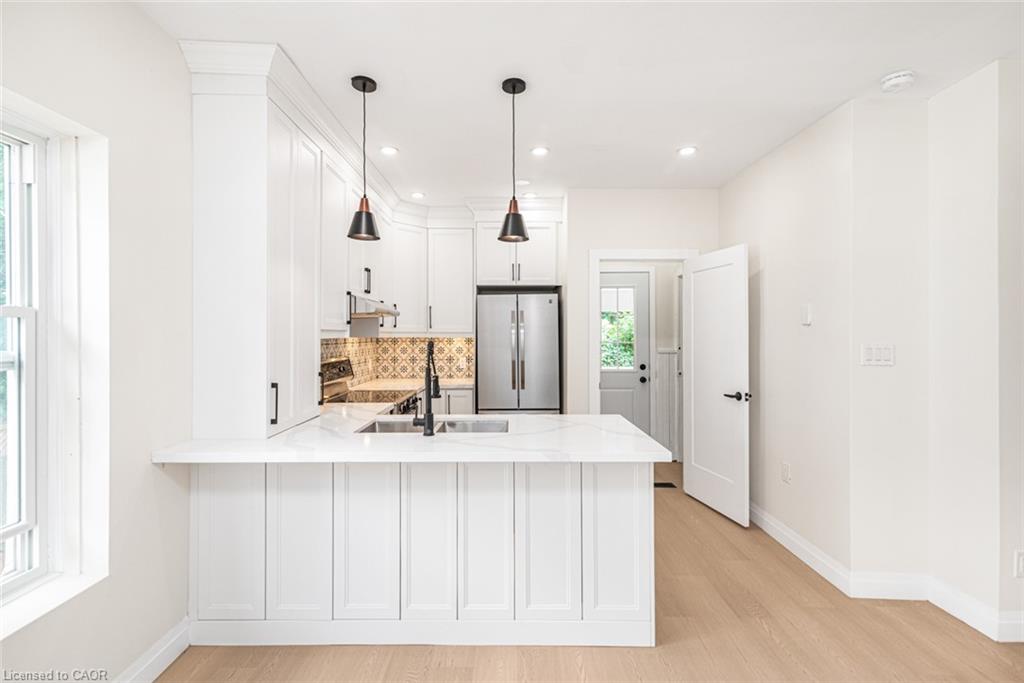 Contemporary kitchen with white shaker cabinetry, stainless steel appliances, a marble-finish countertop, and a decorative tile backsplash