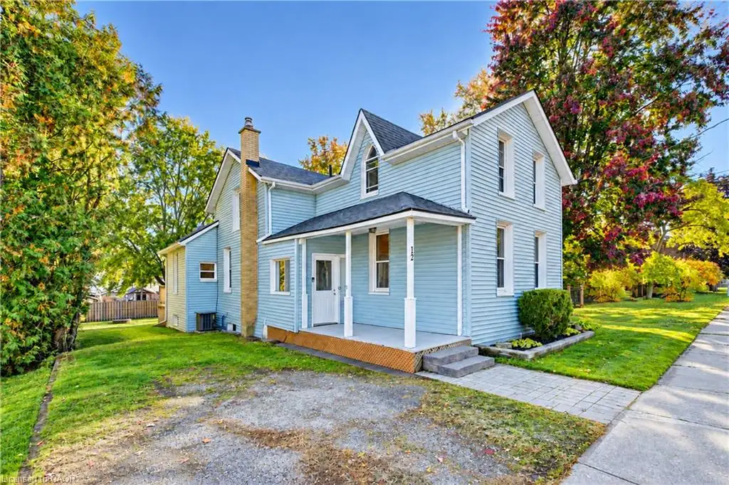 Two-story residence featuring light blue siding, a covered front porch with white columns, an exterior brick chimney, and a multi-gabled roofline