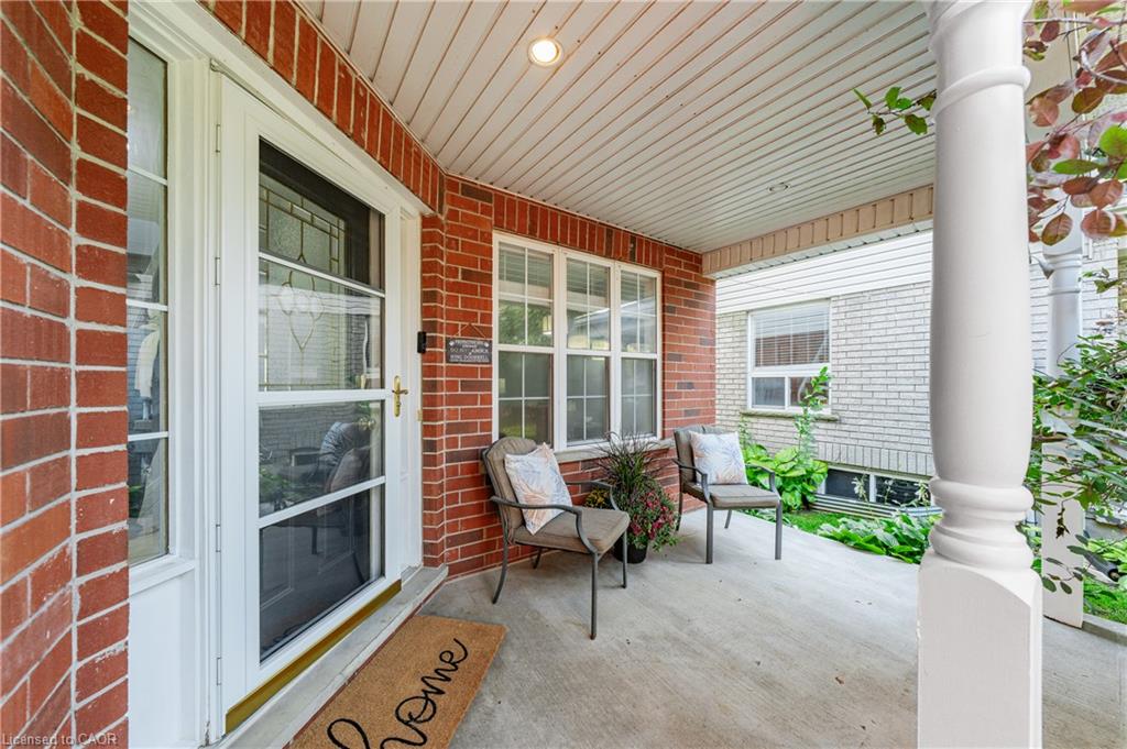Brick exterior featuring a covered porch with a white column, concrete flooring, and multiple windows