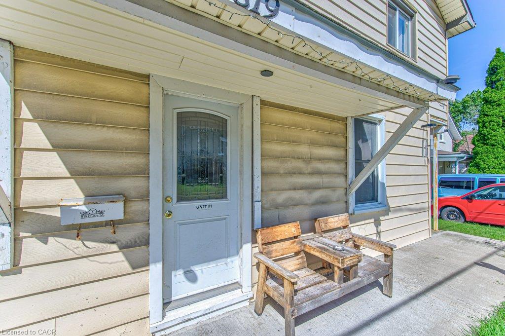 Exterior entrance featuring a light-colored door with an arched glass insert, horizontal siding, and a covered porch area