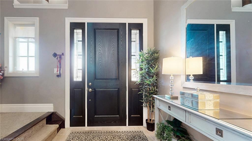 Entryway featuring a dark wood-finish door with sidelights, a framed mirror, and a console table with a glass top