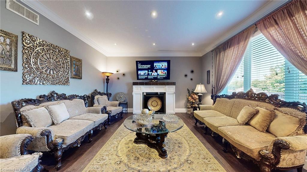 Spacious living area featuring wood-finish flooring, recessed lighting, crown molding, and a white mantelpiece