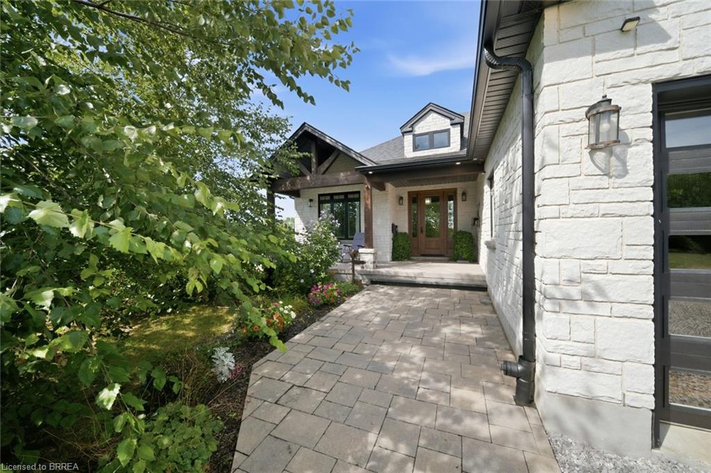 Light-toned stone exterior with black-framed windows, a wood-paneled front door, and a paver walkway