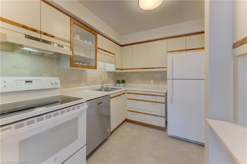 Full kitchen with light-toned cabinetry, stainless steel dishwasher, white range, and stone-finish flooring
