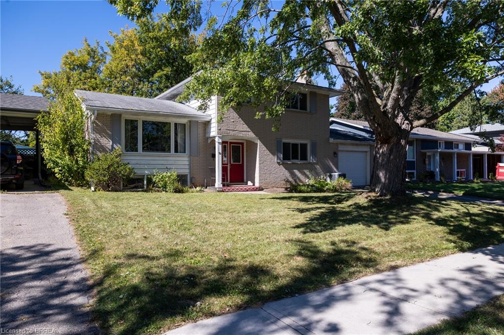 Split-level residence featuring a red entry door, attached single-car garage, and a covered carport