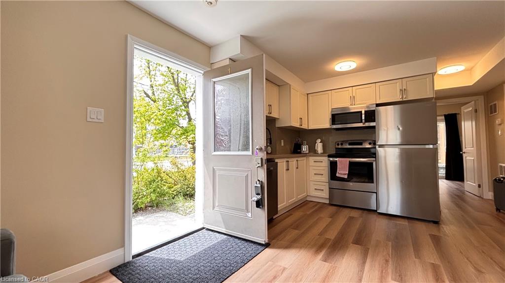Compact kitchen with light cabinetry, stainless steel appliances, and wood-finish flooring
