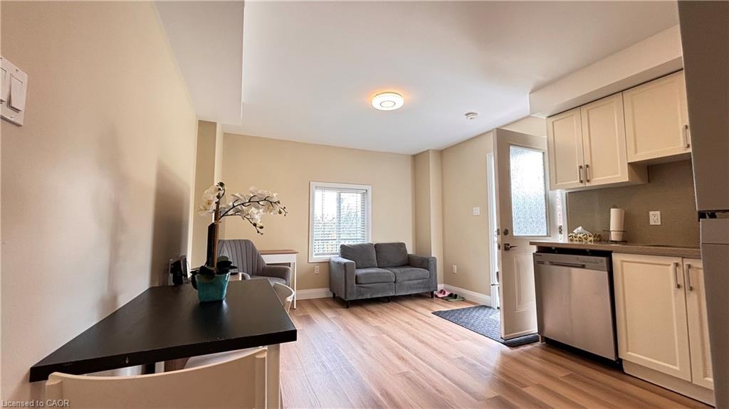 Integrated kitchen area with white cabinetry, stainless steel dishwasher, and countertop