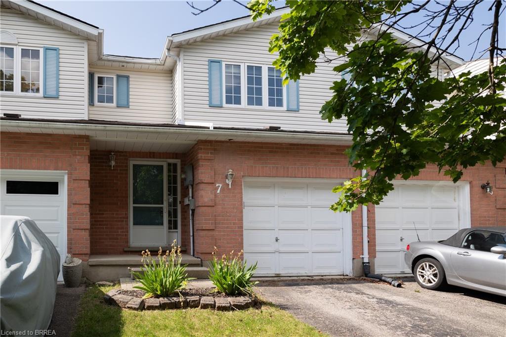 Brick and siding townhouse exterior featuring multiple white garage doors, a covered entry, and light blue window shutters