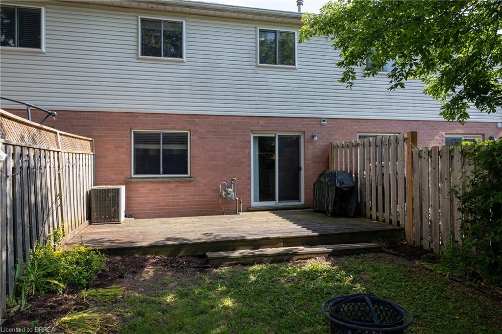Rear exterior featuring a wood deck, brick lower level, and light-colored siding
