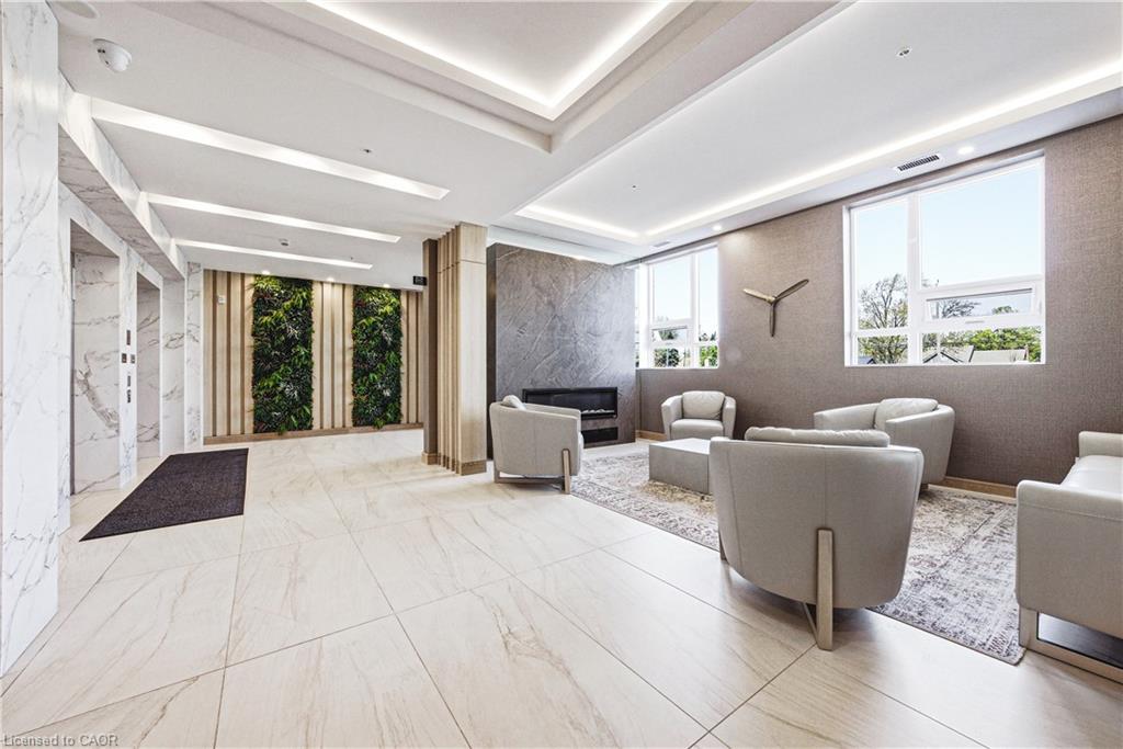 Lobby area featuring large format light-toned tile flooring, recessed ceiling lighting, a textured accent wall with an integrated electric fireplace, and a vertical garden wall