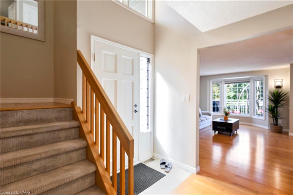 Hardwood flooring, bay window, natural light, carpeted staircase, and wood handrail