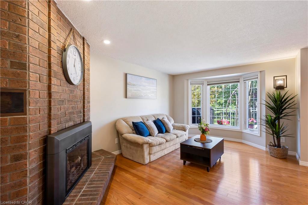 Brick fireplace with hearth, hardwood flooring, and a bay window