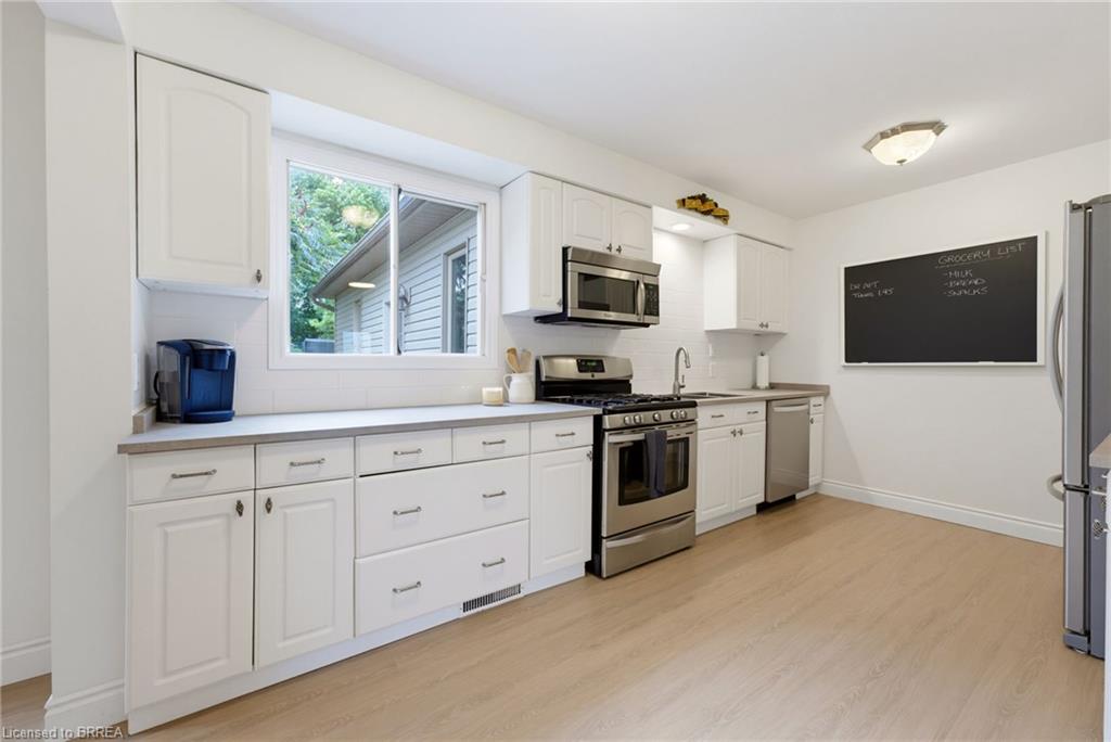 White shaker cabinetry with stainless steel appliances, light-toned wood-finish flooring, and a white subway tile backsplash