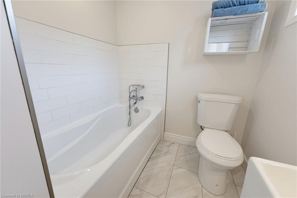White subway tile surround, built-in bathtub with chrome fixtures, and light-toned tile flooring