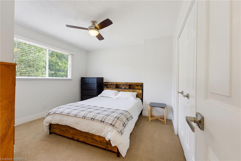 Recessed window with blinds, ceiling fan with integrated lighting, textured ceiling, light-colored carpeting, white paneled door