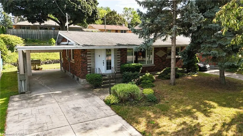 Brick exterior, attached carport, concrete driveway, mature trees, and landscaped front yard