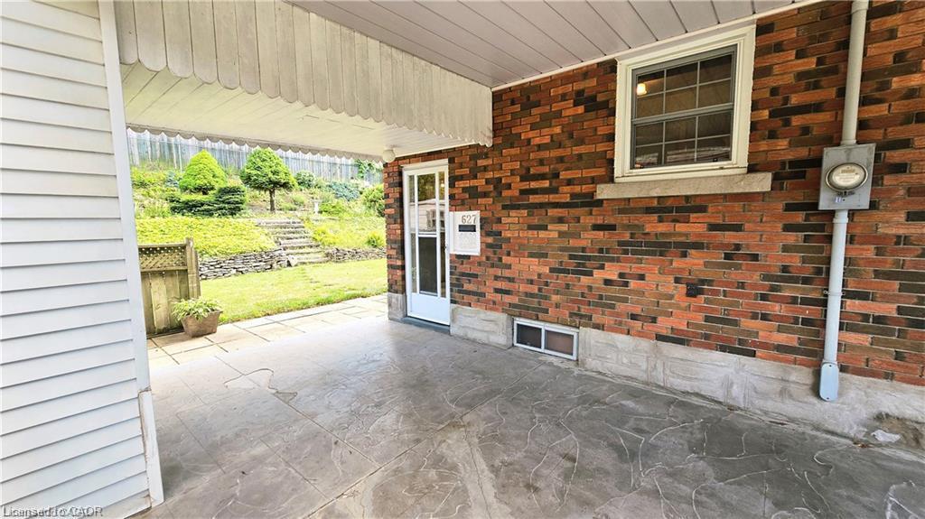 Covered patio with stamped concrete flooring, brick exterior, and a landscaped terraced yard