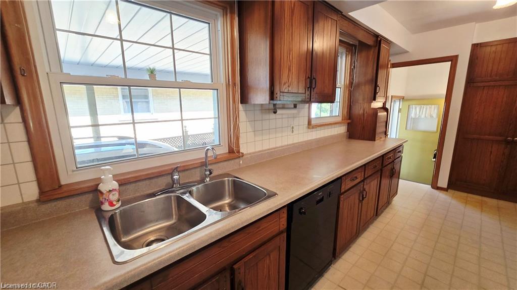 Kitchen featuring wood cabinetry, a double basin stainless steel sink, a dishwasher, and a window with grid pattern