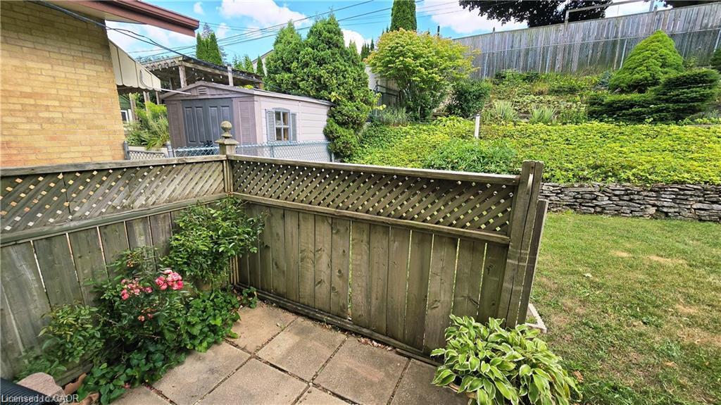 Patio area with paving stones, wood privacy fencing, and garden beds