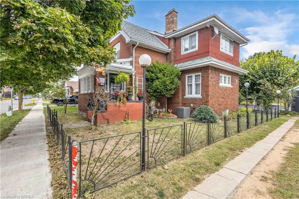 Brick exterior with white trim, featuring multiple windows and a decorative wrought iron fence