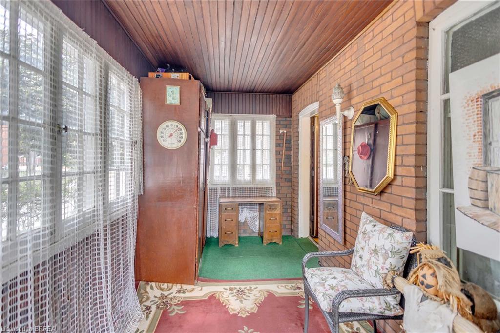 Enclosed porch featuring wood panel ceiling, brick accent wall, multiple windows, and wood-finish flooring