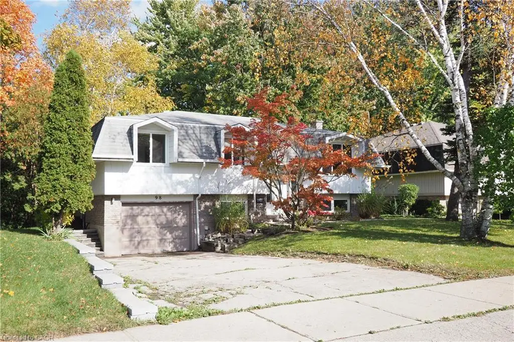 Split-level exterior featuring white siding, stone veneer lower level, dual dormer windows, and garage