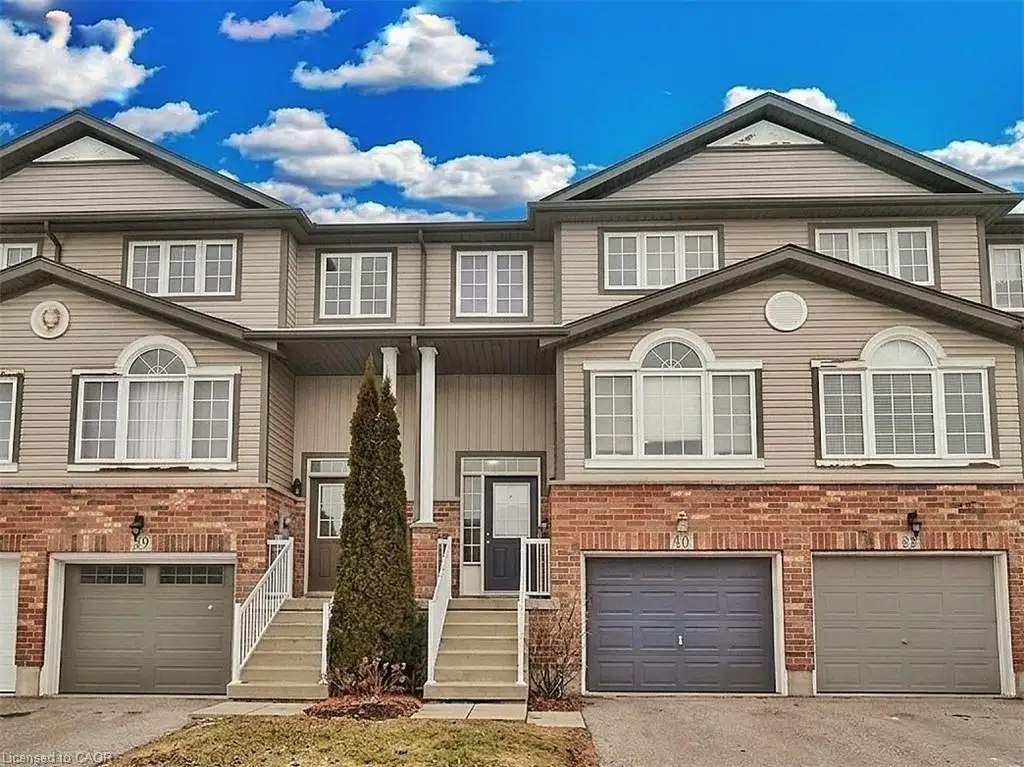 Townhome exterior featuring tan siding and brick accents