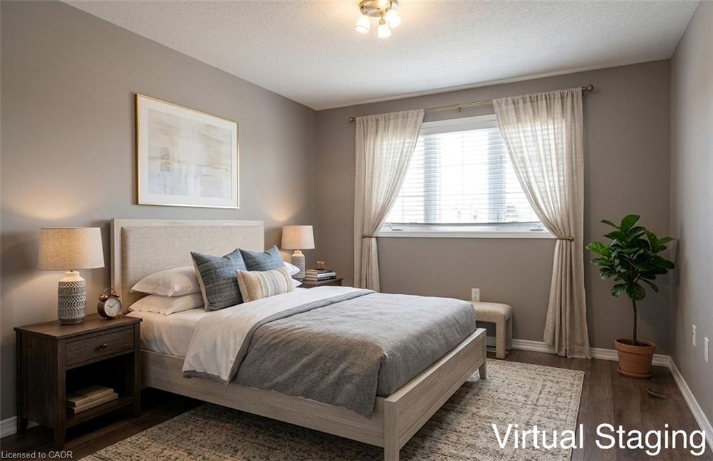 Spacious bedroom featuring warm gray walls, wood-finish flooring, a large window with blinds and drapes, and a built-in overhead light fixture