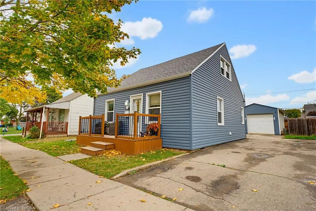 Blue horizontal vinyl siding exterior featuring a covered wood front porch, gable roofline, concrete driveway, and detached single-car garage