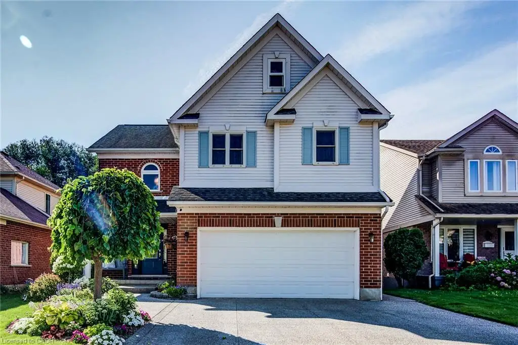 Multi-level exterior featuring a brick and horizontal siding facade, a two-car garage, shutter-framed windows, and a paved driveway