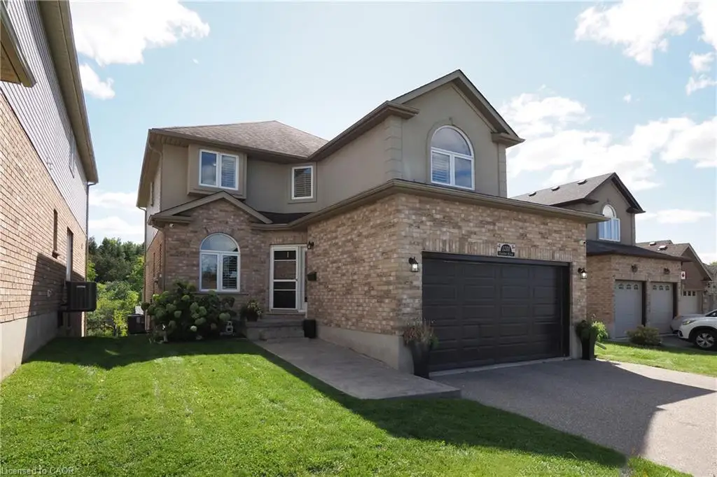 Brick and stucco exterior, arched window, attached two-car garage, concrete walkway, and asphalt driveway