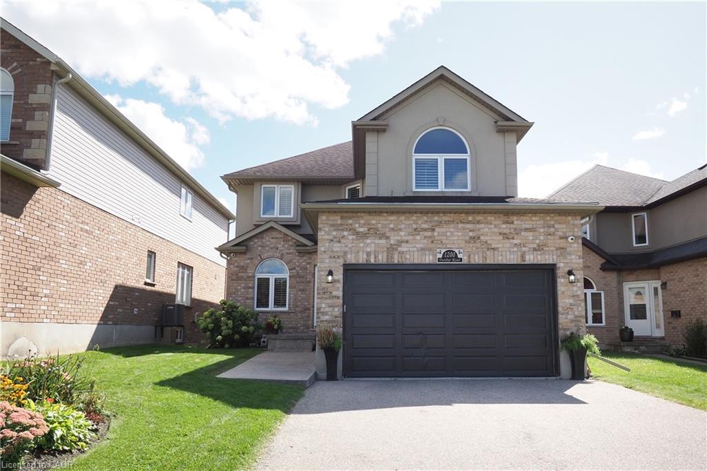 Brick and stucco exterior with an arched window, a two-car garage, and concrete driveway