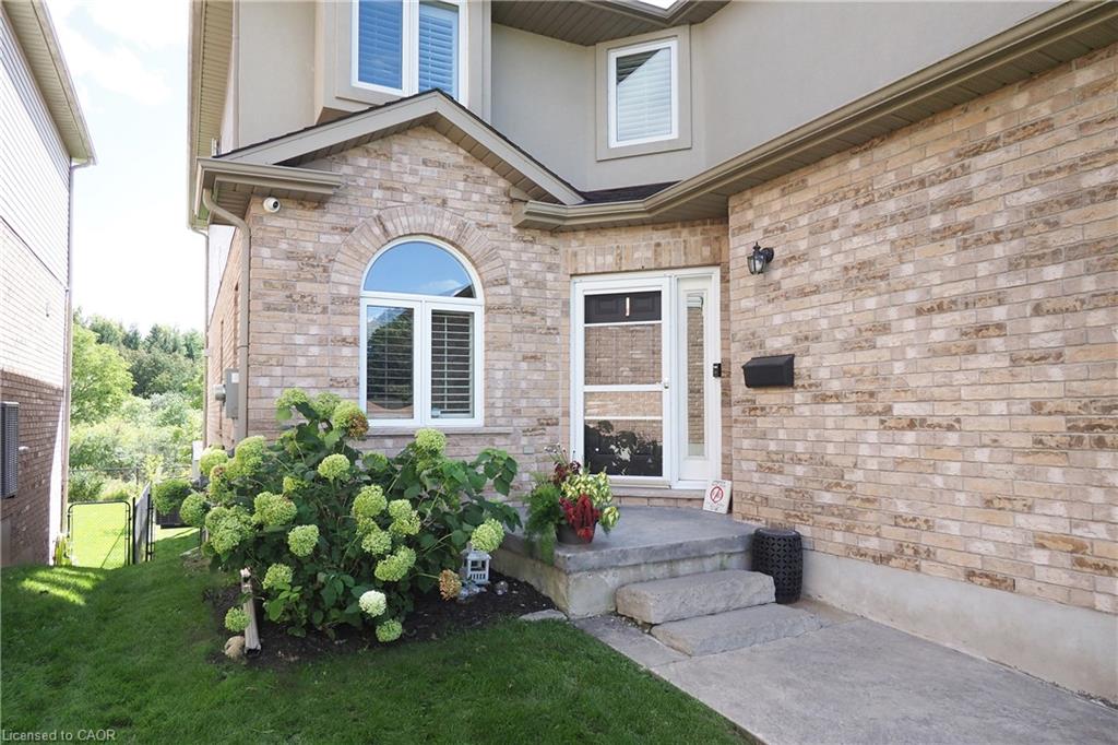 Brick exterior with arched window, concrete steps, and a landscaped garden bed