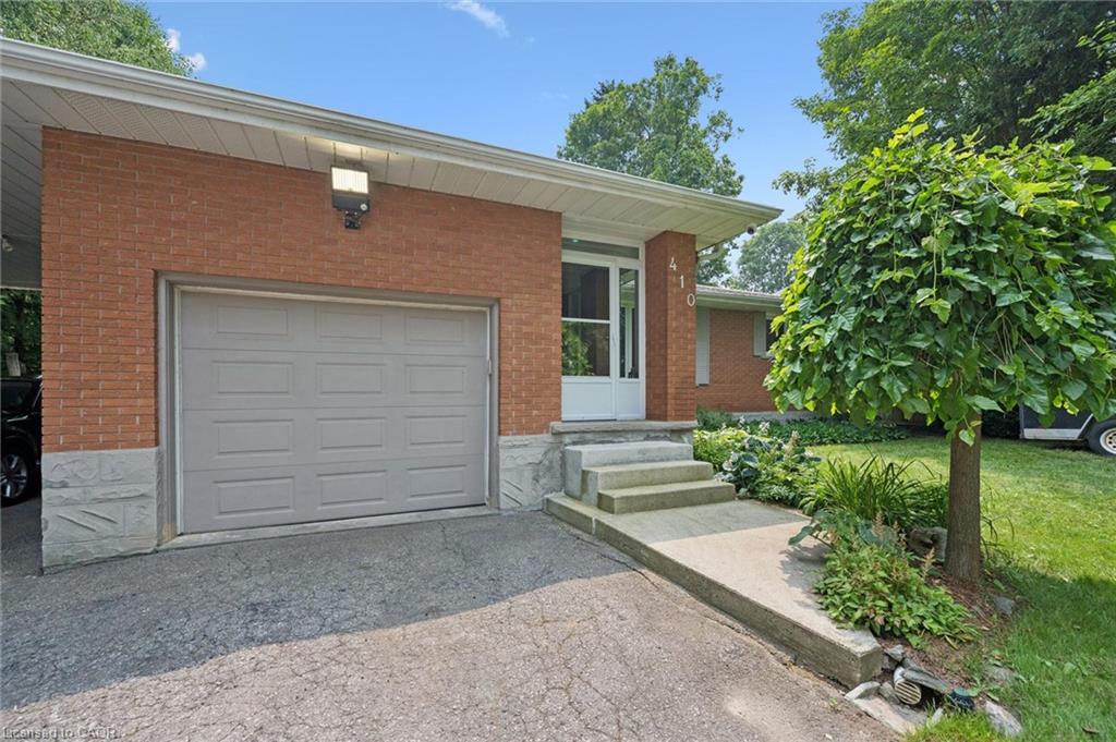 Brick facade residence featuring a single-cargarage with a panel door and large LED exteriorlighting