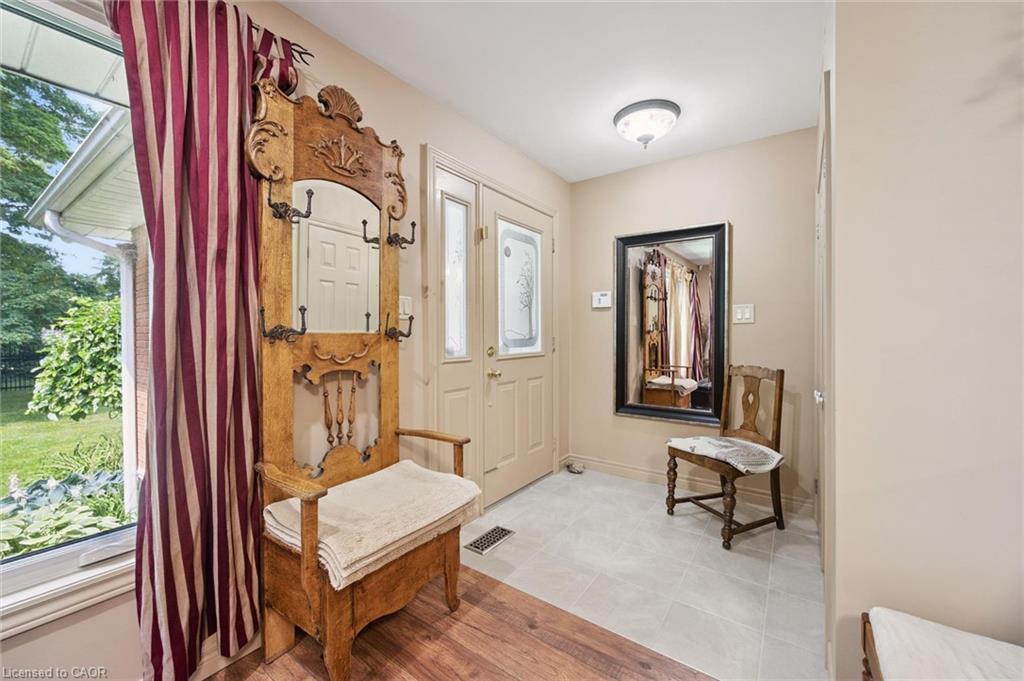 Entryway featuring a door with decorative glass inserts, light grey floor tiling, and neutral wall tones, glass inserts, light grey ceramic floor tiling and neutral wall tones