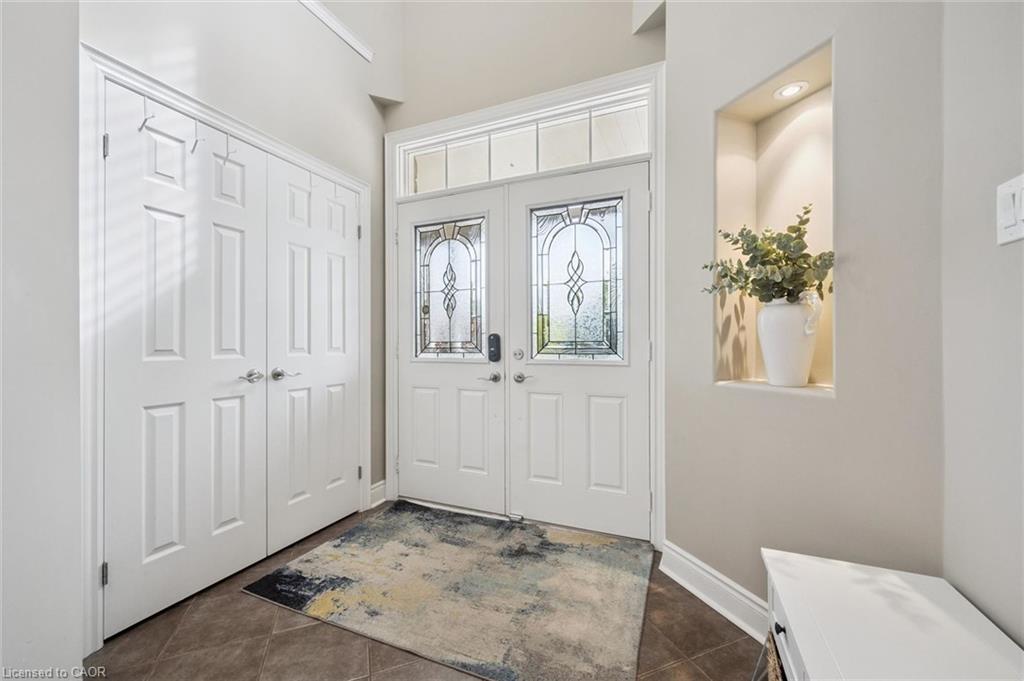 Double entry doors with decorative glass panels, transom window, recessed wall niche with lighting, and tiled flooring