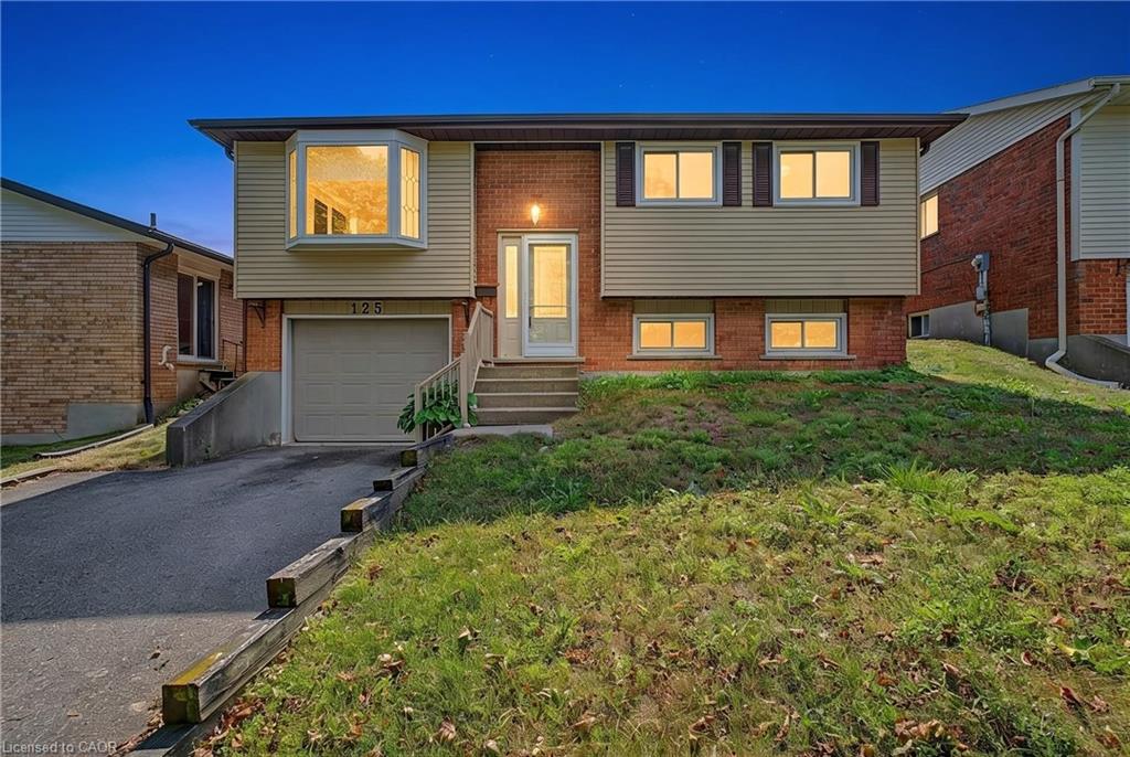 Brick and siding exterior featuring an attached garage, paved driveway, and a front bay window