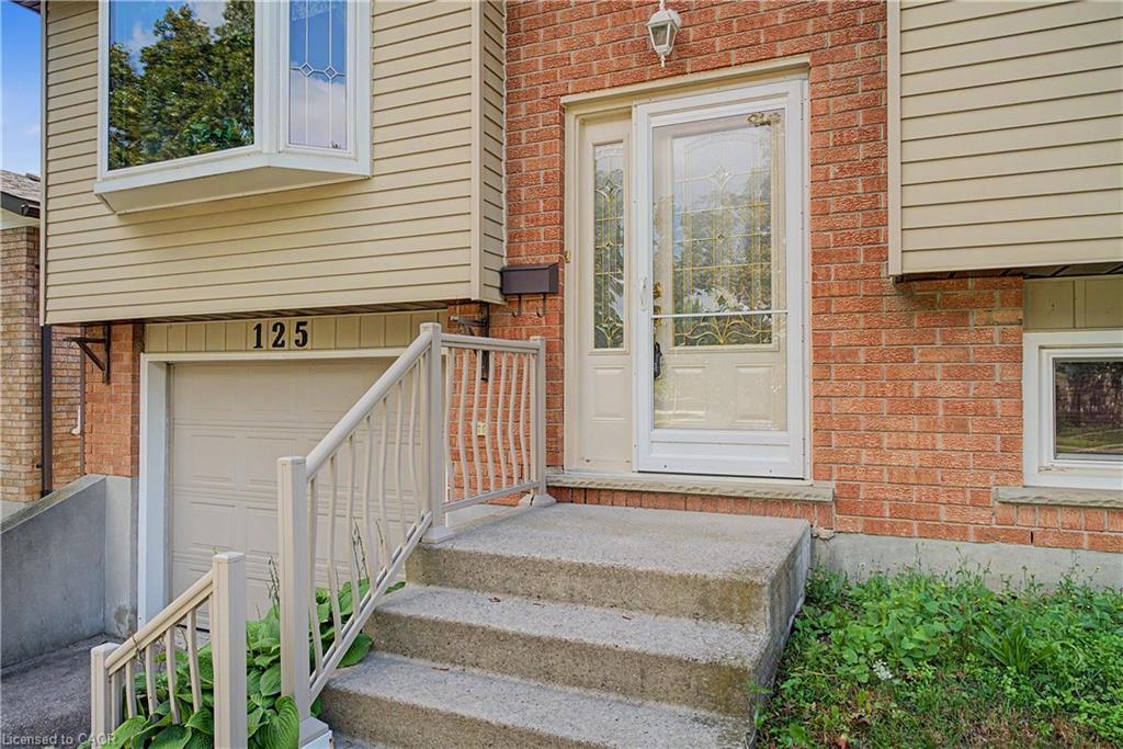 Brick and siding exterior featuring a bay window, garage door, and concrete steps with railings