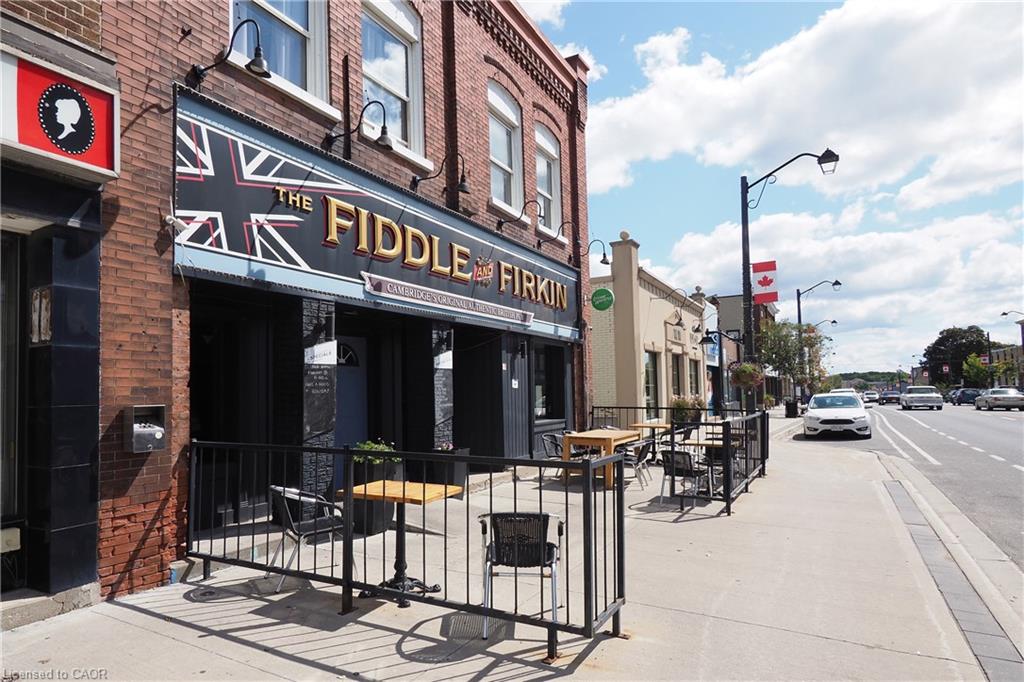 Brick facade commercial building with a prominent storefront, exterior lighting fixtures, and an outdoor patio area enclosed by black railings