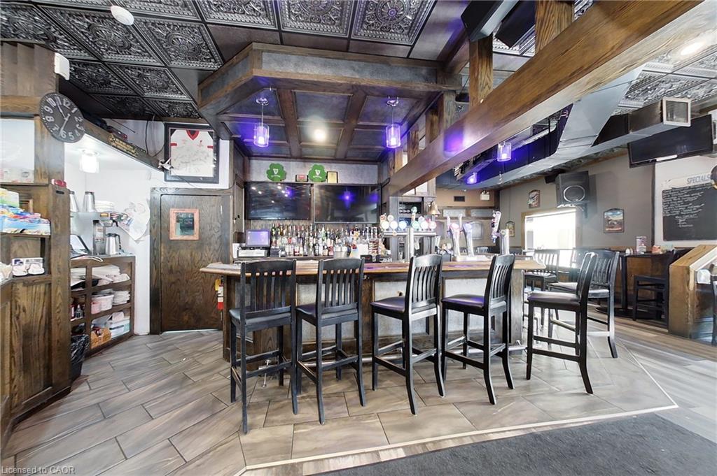 Detailed patterned ceiling, wood-finish flooring, built-in wooden bar, integrated overhead lighting, and multiple mounted screens
