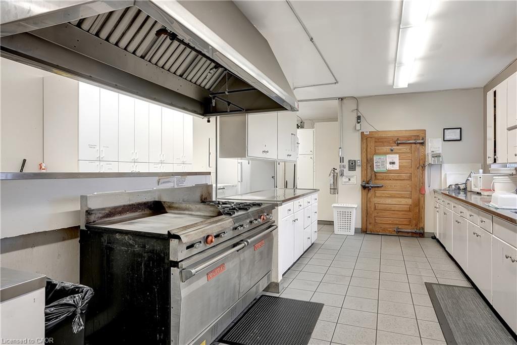 The kitchen features extensive white cabinetry, stainless steel countertops, and a large commercial-grade range with an overhead exhaust hood