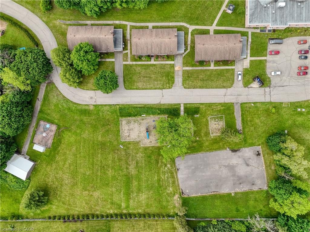 Aerial view showcasing the property's surroundings, including paved roads, a parking lot, and extensive green spaces with mature trees